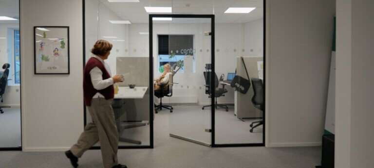 kvinne spaserer på kontor, drikker kaffe